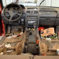 filthy car interior with rubbish strewn about